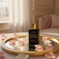 Perfume spray bottle on mirrored vanity tray with rose petals in golden hour light